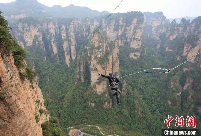 户外运动爱好者张家界峰林间挑战高空荡绳