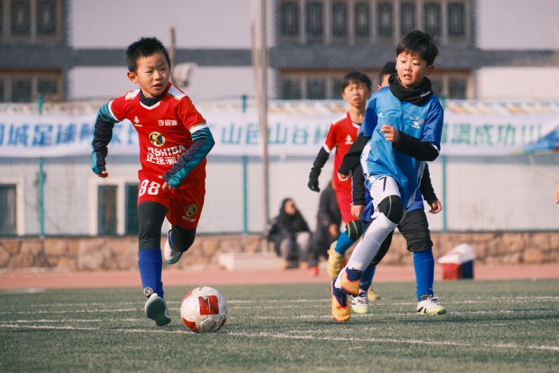 山东青岛:足球贺岁启新程 2026年1月1日,在山东省青岛市城阳区夏庄街道山色峪乡村振兴齐鲁样板省级片区举办的足球邀请赛上,足球小将在带球进攻。