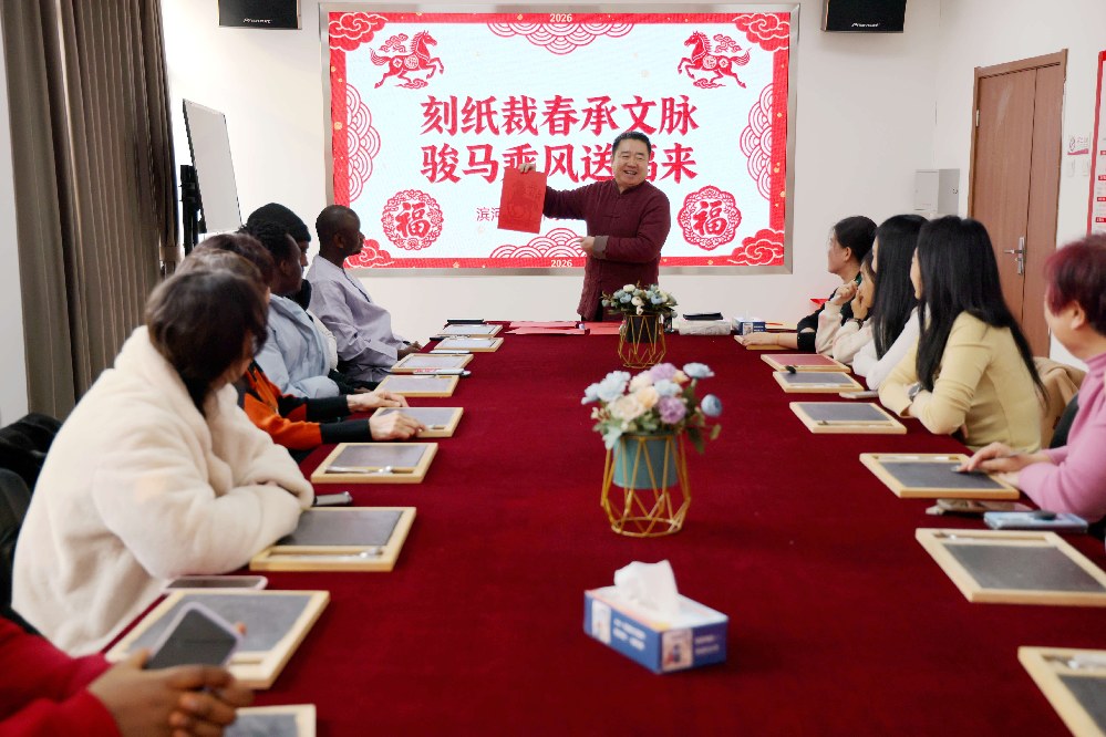 市级非物质文化遗产项目刻纸艺术代表性传承人马振领为留学生及居民讲解刻纸的技巧。王杰摄