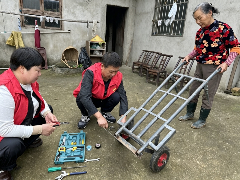 办好“微实事” 服务“大民生” 驻村工作队员为老人修推车。