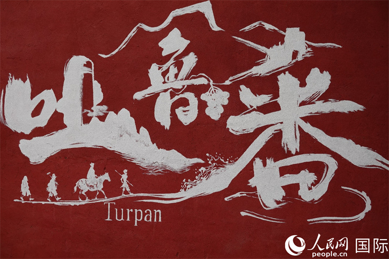 一幅绘有吐鲁番及其中文名“吐鲁番”的壁画，以及中国古典名著《西游记》中发生在吐鲁番的著名场景。人民网记者 王禹蘅摄