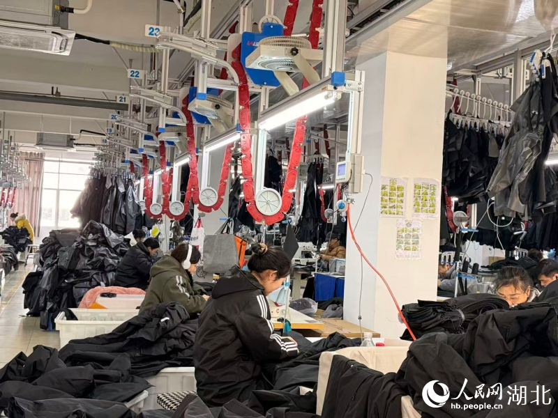 湖北奥瑟夫制衣有限公司的车间里，四条银灰色的“空中走廊”——吊挂系统有序运转。人民网记者 张隽摄